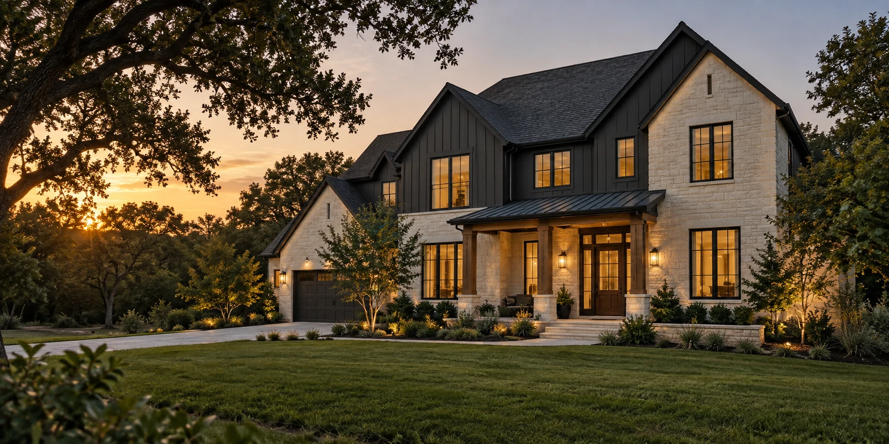 A newly built stone and charcoal home surrounded by mature trees at sunset